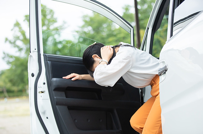 車からでてきながら、首をおさえている女性